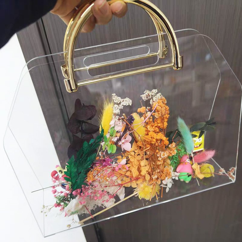 Clear acrylic flower box with golden metal handle filled with colorful preserved flowers
